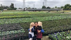 A Montessori teacher and young students at an outdoor plant nursery in Los Angeles, USA, demonstrating hands-on nature education